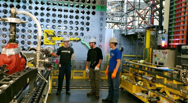 A trades instructor works with two boilermakers and a millwright during calandria tube installation training in the DEC mock-up.