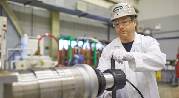 A worker inspects a new fuel channel assembly.