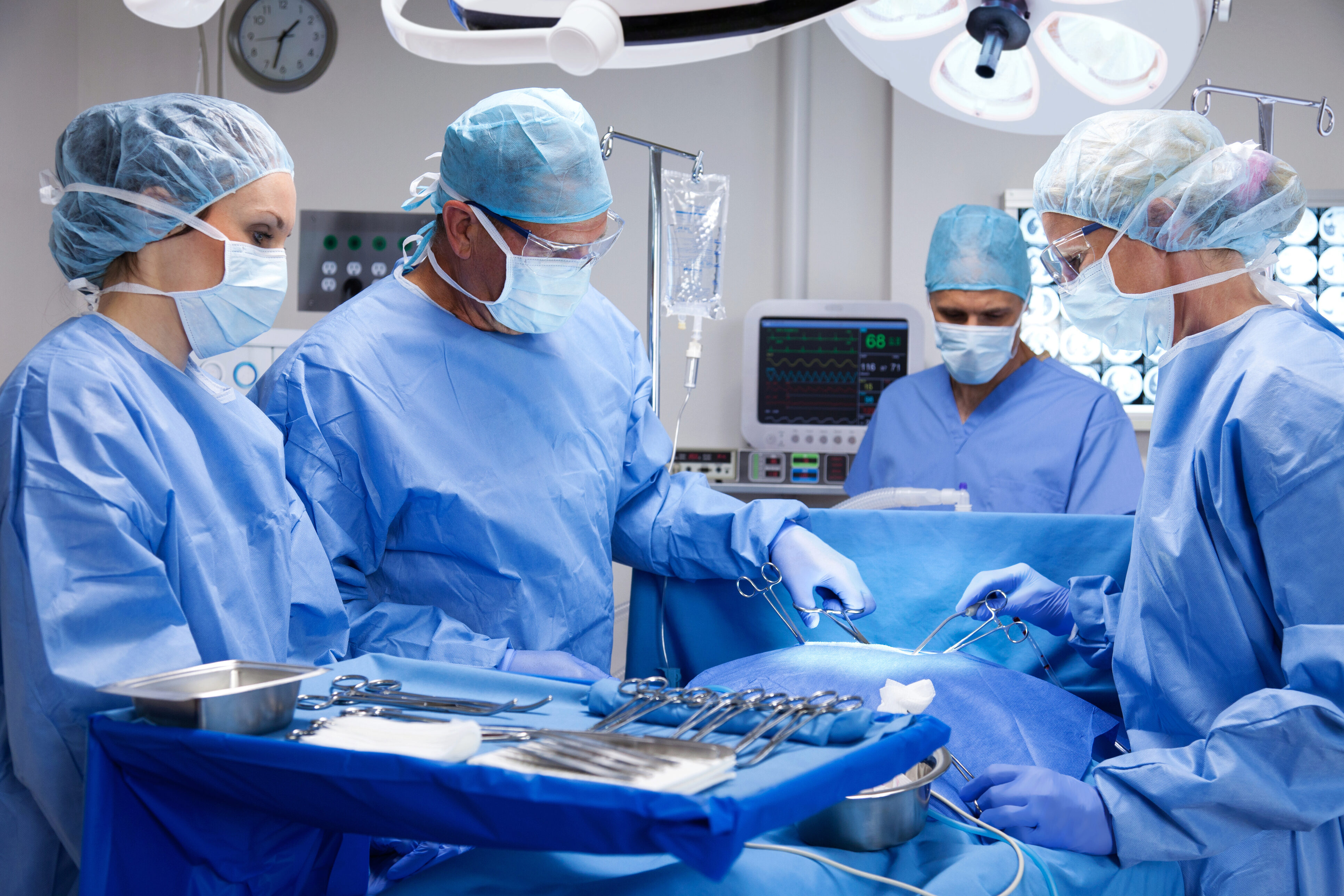 A surgical team gathered around a tray of sterlized medical equipment.