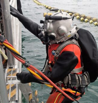 Man in scuba gear climbing out of water back onto the boat.