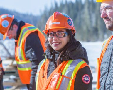 Employee Ginny Ly smiles at the camera while outside surrounded by co-workers.