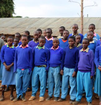 Simon Kariuki standing with a group of students in Kenya. where he strives to end poverty.
