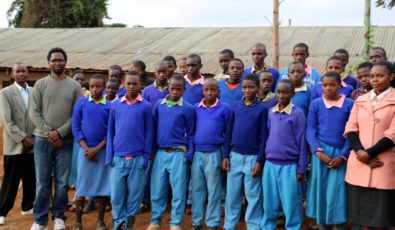 Simon Kariuki standing with a group of students in Kenya. where he strives to end poverty.