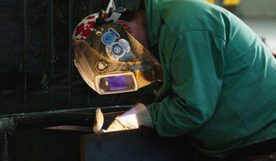 A worker in a protective helpment performs welding work.
