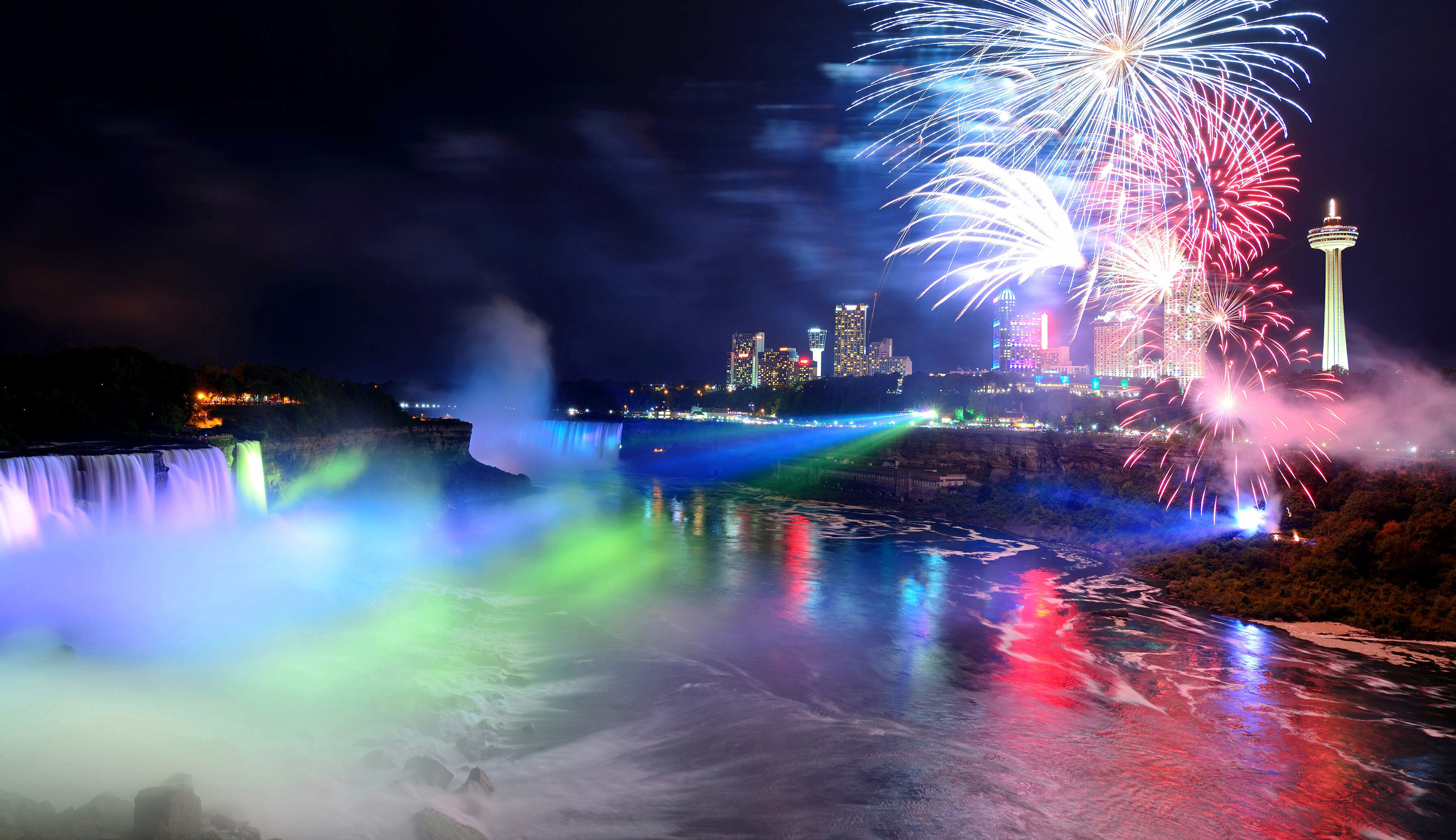 Fireworks explode in the air at night above horseshoe falls in Niagara Falls.