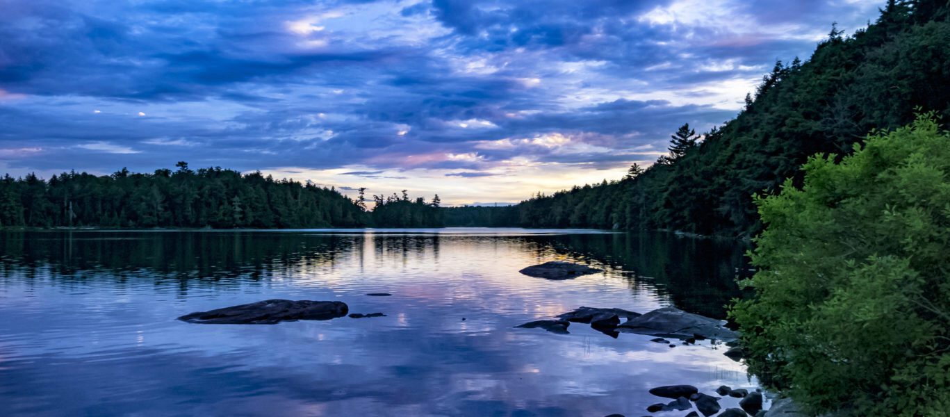 Dusk over a picturesque lake reflecting a blue overcast sky.