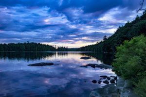 Dusk over a picturesque lake reflecting a blue overcast sky.