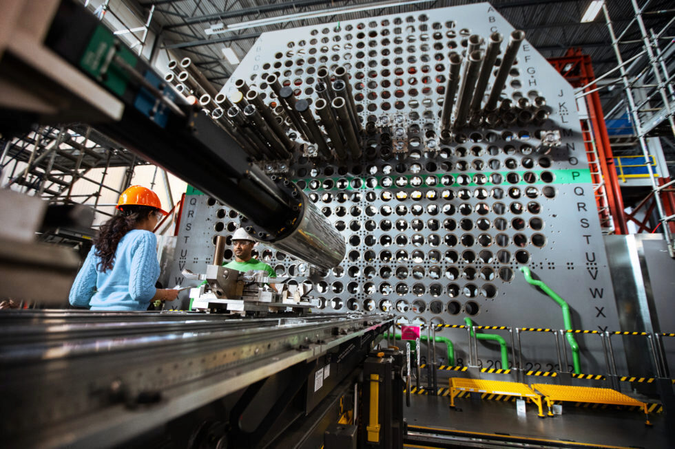 Workers in hard hats train for their work on a full-scale nuclear reactor mock-up.