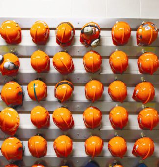 A large collection of orange hard hats hanging on a wall.