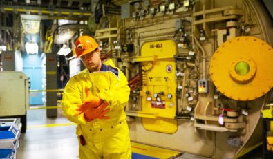 A worker in protective plastic clothing stands outside an airlock at the Pickering Nuclear Generating Station.