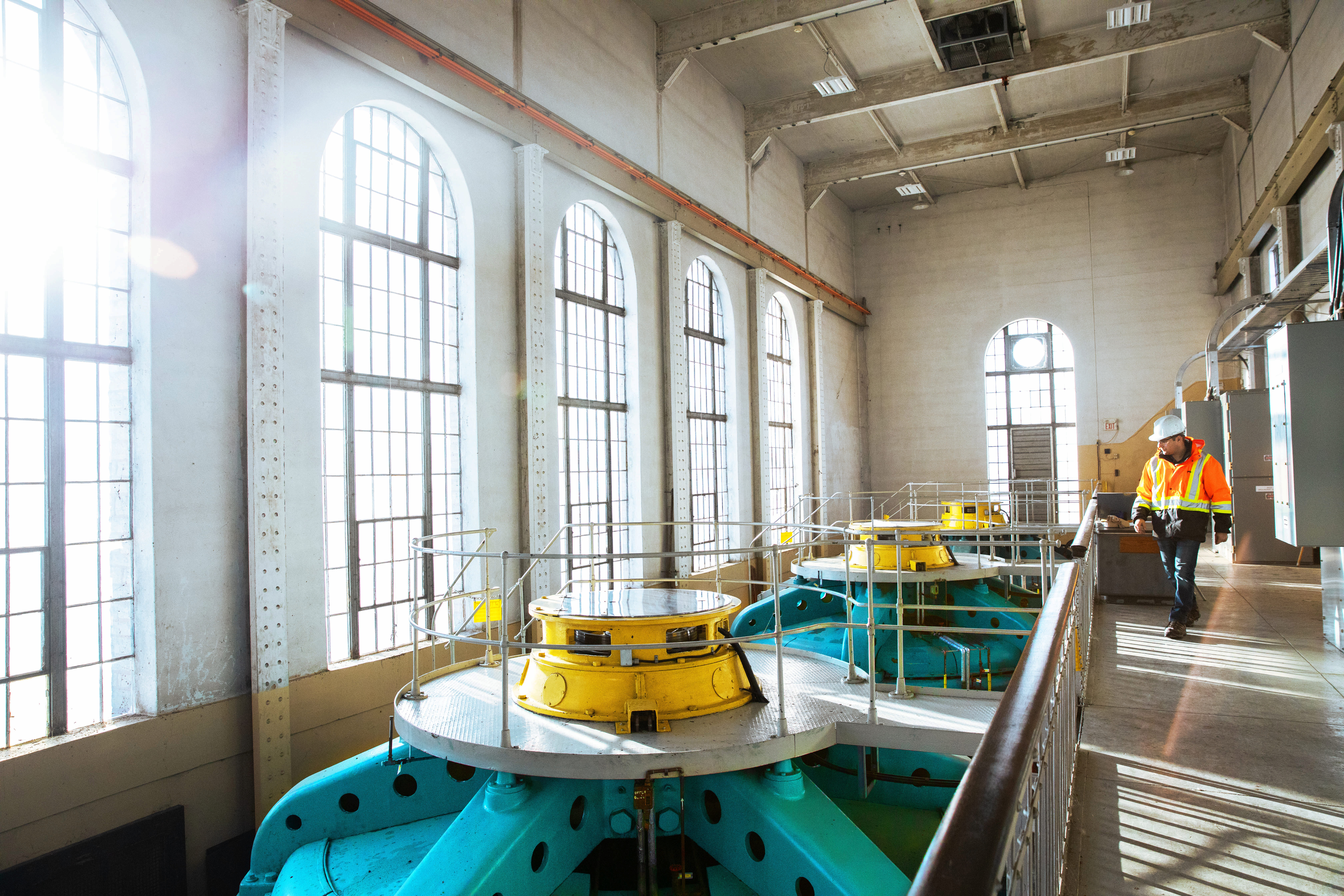 A worker in safety gear looks down on turbines at Ranney Falls hydroelectric station.