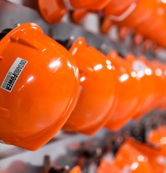 A long row of orange hard hats hanging on a wall.