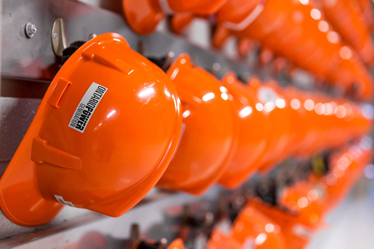 A long row of orange hard hats hanging on a wall.