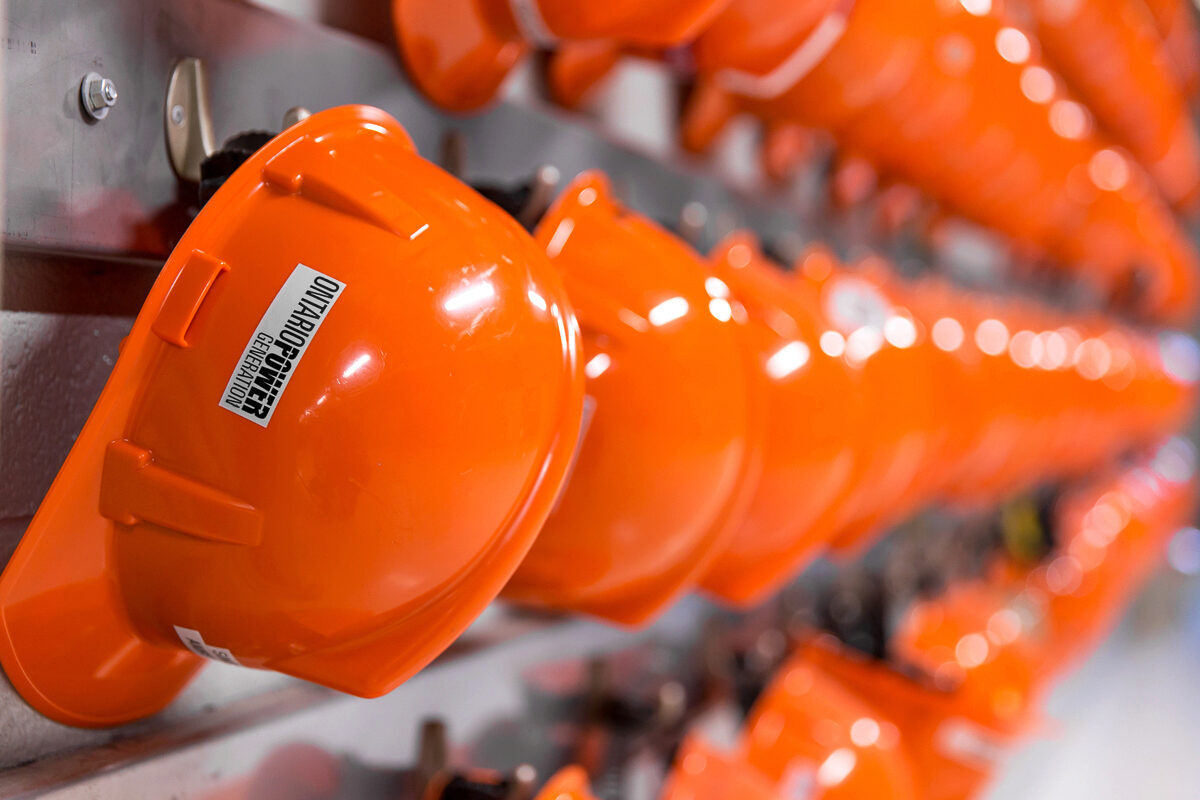A long row of orange hard hats hanging on a wall.