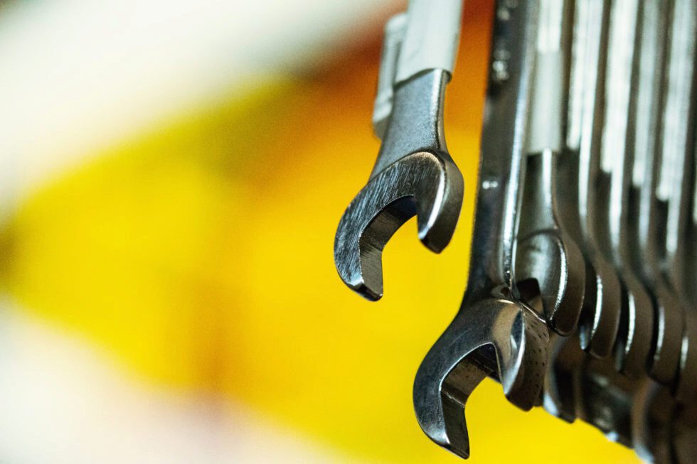 A collection of wrenches from up close against a bright yellow background.