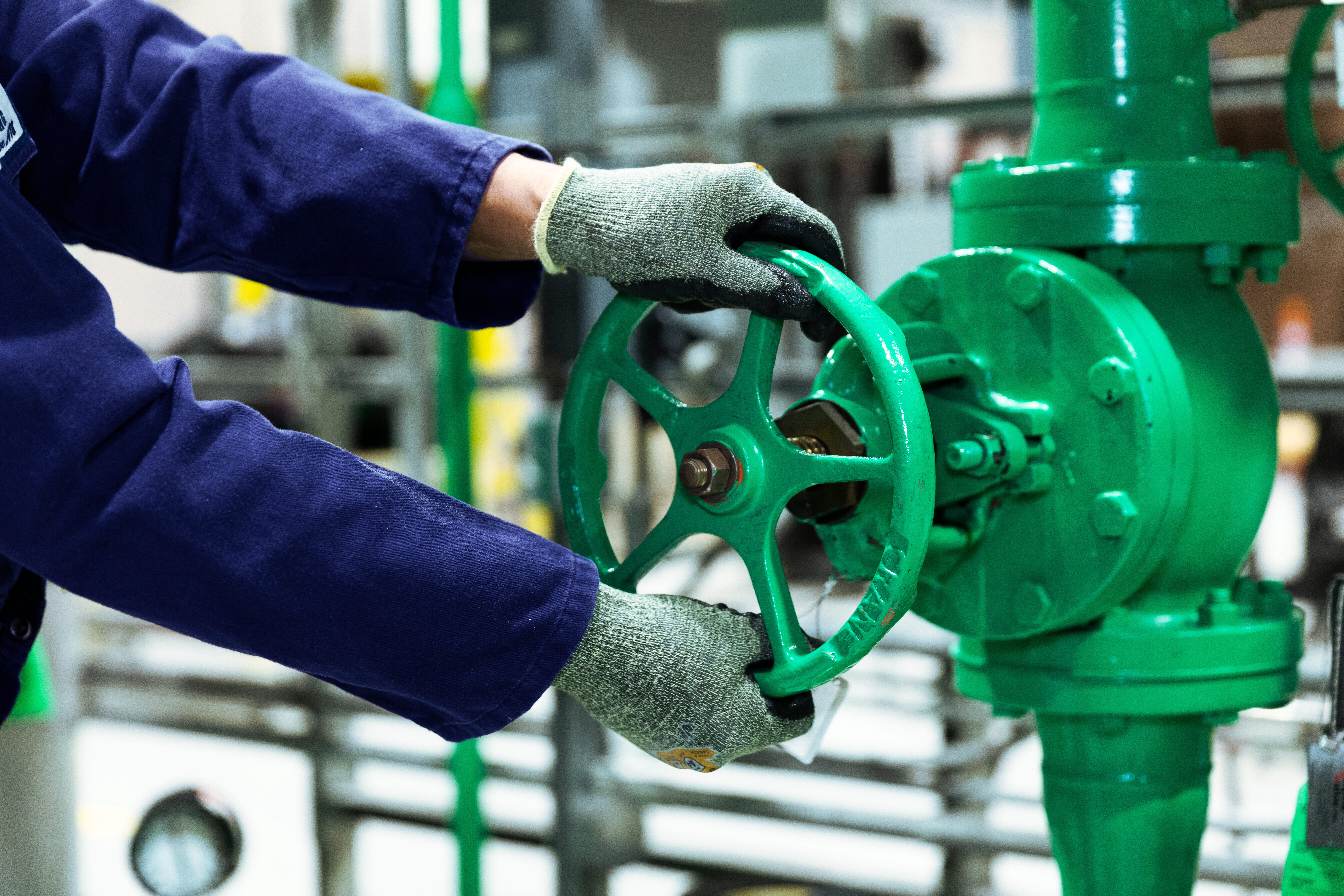 A worker's hands on a bright green valve.
