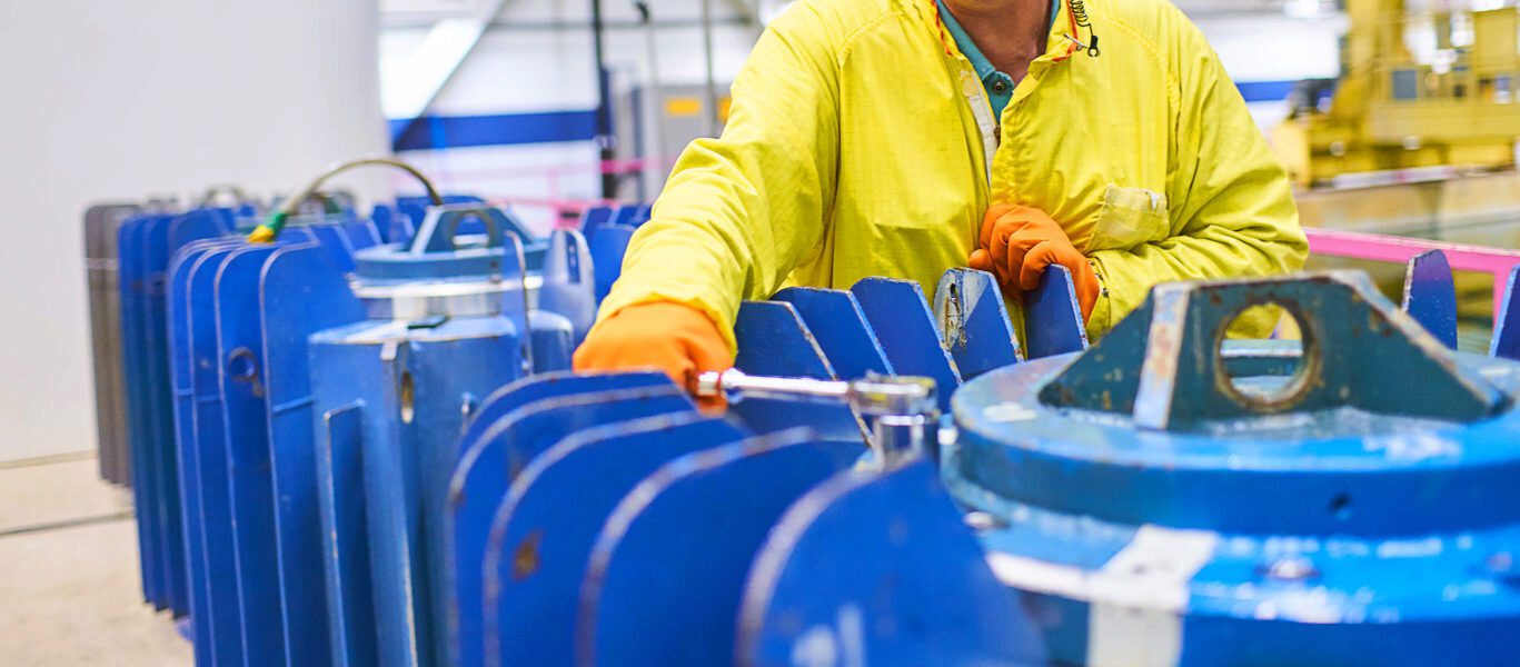 A worker in protective clothing works on nuclear isotope harvesting.