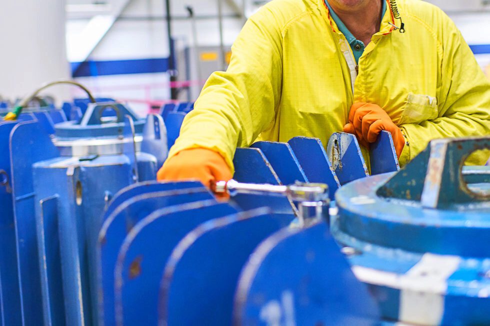 A worker in protective clothing works on nuclear isotope harvesting.