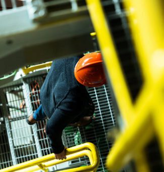Looking down on a worker in coveralls and a hard hat as they climb stairs.