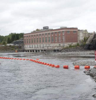 A motorboat approaches a water safety boom near our Alexander Generating Station.