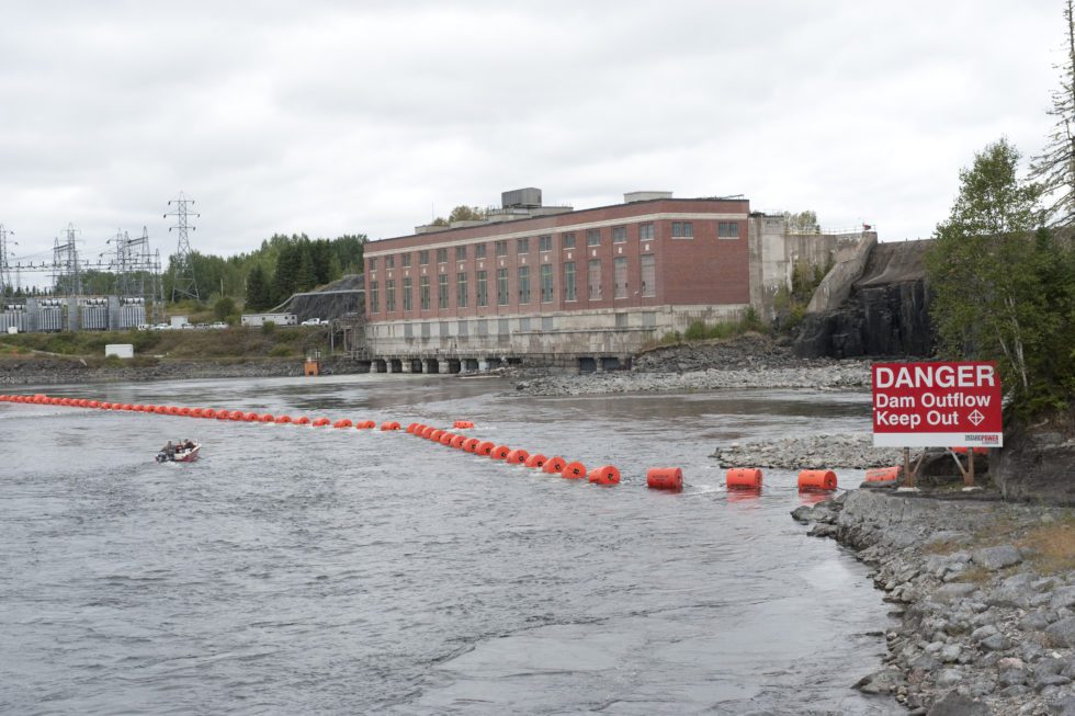 A motorboat approaches a water safety boom near our Alexander Generating Station.