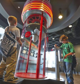 Two kids spin handles on a generator exhibit.
