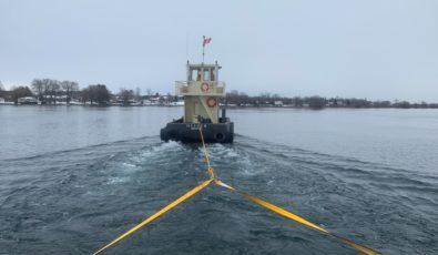 A tugboat helps with the installation of ice booms on the St. Lawrence River.