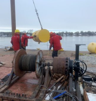 Workers from Kehoe Marine Construction maneuver a steel pontoon during installation of the ice boom on the St. Lawrence River.