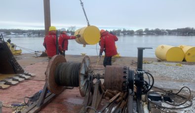 Workers from Kehoe Marine Construction maneuver a steel pontoon during installation of the ice boom on the St. Lawrence River.