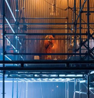 Welder working on boiler on scaffolding.