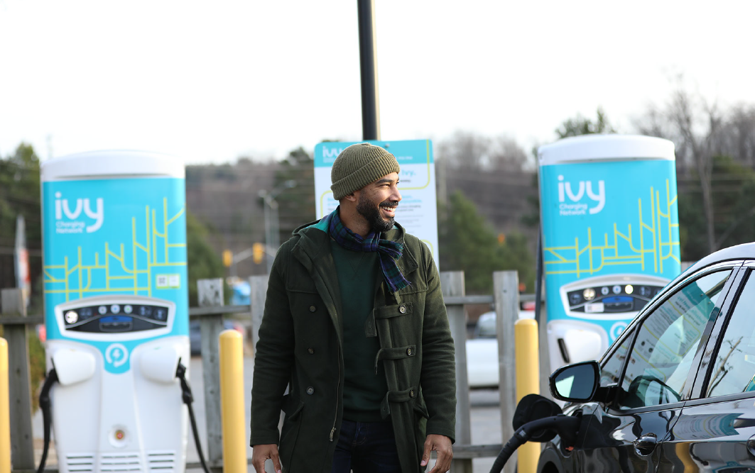 A man charging his electric vehicle at an Ivy Charging Network EV charging station.