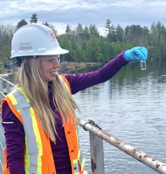 Carly Lance, a Junior Health, Safety and Environment Assistant with contractor M. Sullivan and Son, examines a water sample at OPG's Calabogie Redevelopment project site.