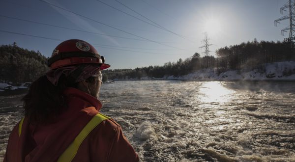 An water manager assesses water conditions near a hydroelectric dam.