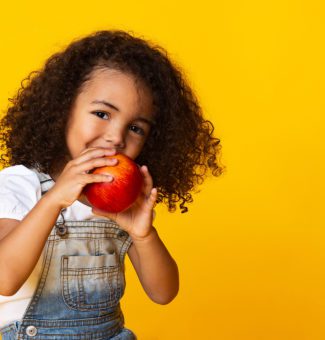 A young girl holding an apple.