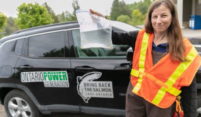 Employee with Ontario Federation of Anglers and Hunters holds up bag with juvenile Atlantic Salmon.