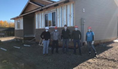 OPG employees stand in front of a new home under construction in Neyaashiinigmiing.