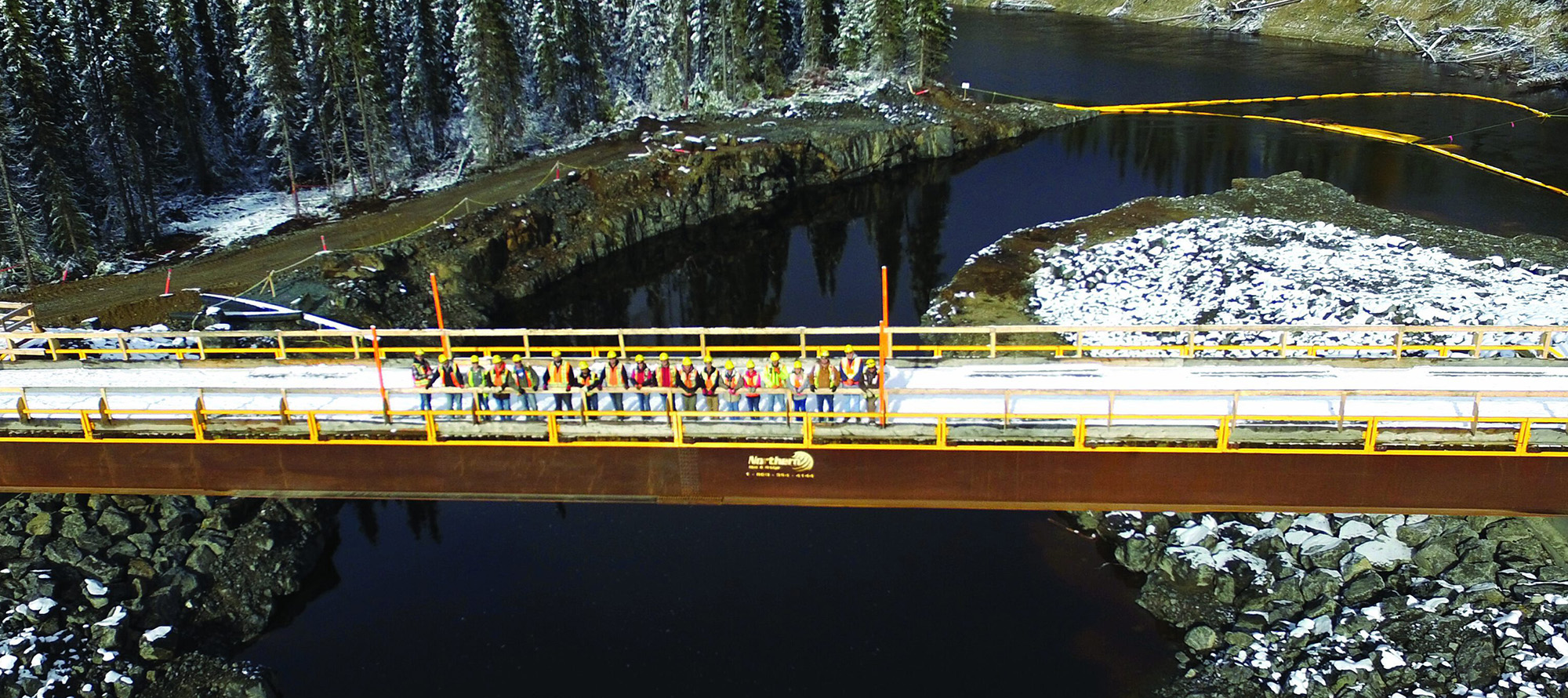 A group of workers gather on a bridge celebrating the successful construction of Peter Sutherland Sr. hydroelectric station.