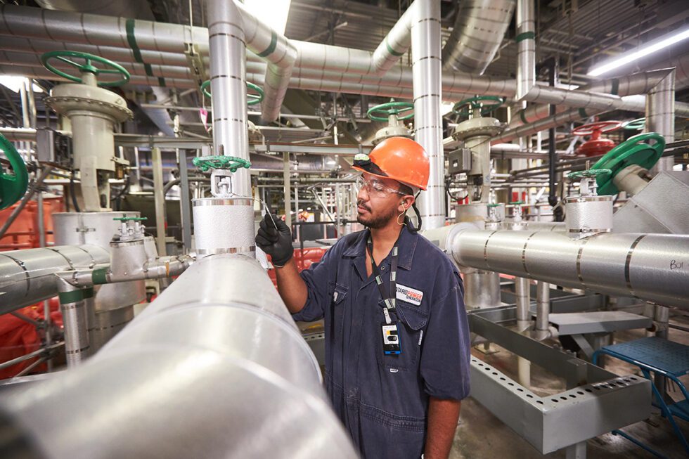 A worker in blues and a hard hat inspects machinery at Darlington Nuclear Generating Station.