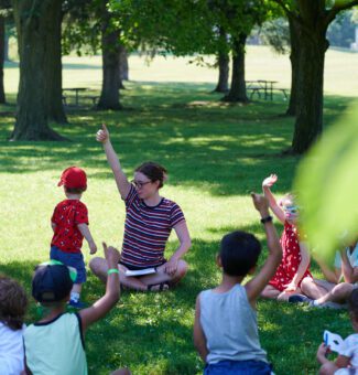 Children take part in a guided activity in a park.