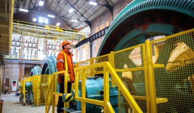 A worker in orange protective gear examines a turbine at Ranney Falls hydroelectric station.