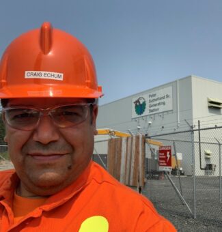 Craig Echum, a Mechanical Technician in OPG’s Abitibi Production group in the northeast, poses in front of OPG's Peter Sutherland Sr. Generating Station.