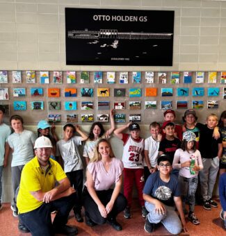 The Grade 4/5 class from Mattawa District Public School pose in front of their artwork at Otto Holden GS.