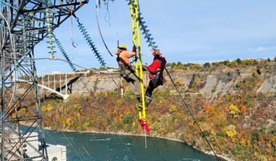 Workers are seen using a suspended ladder and safety harnesses as they replace insulators that have reached the end of their service life at Sir Adam Beck II Generating Station in Niagara Falls.