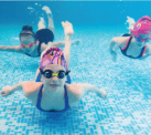 Kinds swimming underwater in a pool.