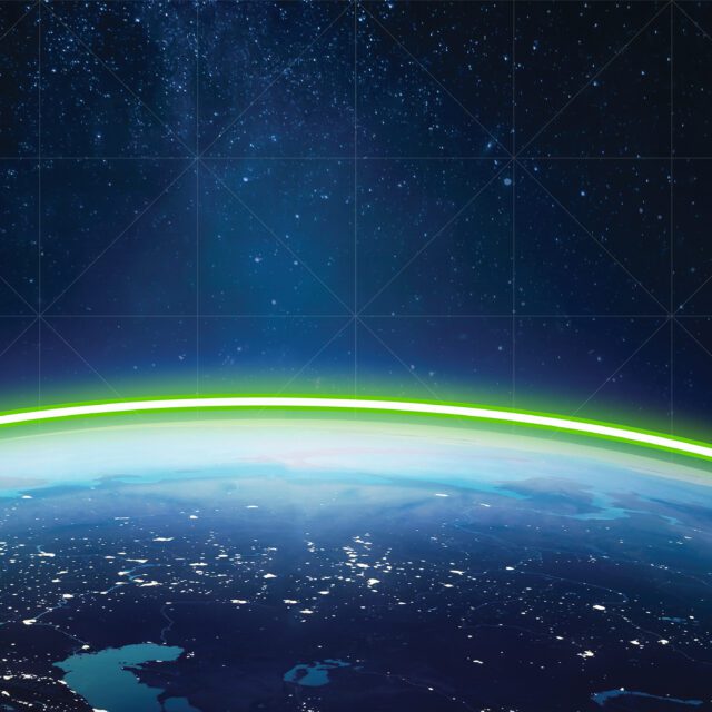 A green energy line crests the horizon of the Earth seen from space.