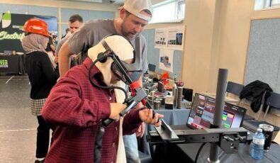 A student tries out a welding simulator at the June "Trades Promoting Trades" event.
