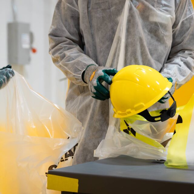 Employee sorting through low-level nuclear waste - yellow hard hat