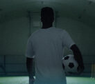 An athlete with a soccer ball in a sports dome.